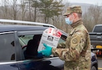 New York Army National Guard Pfc. Colton Emmett, an infantryman assigned to Delta Company, 2nd Battalion, 108th Infantry Regiment, hands out care packages while distributing food in Delhi, N.Y., April 30, 2020. The Soldiers assisted volunteers as they sorted, packaged and handed out numerous dairy products at a drive-through donation center.