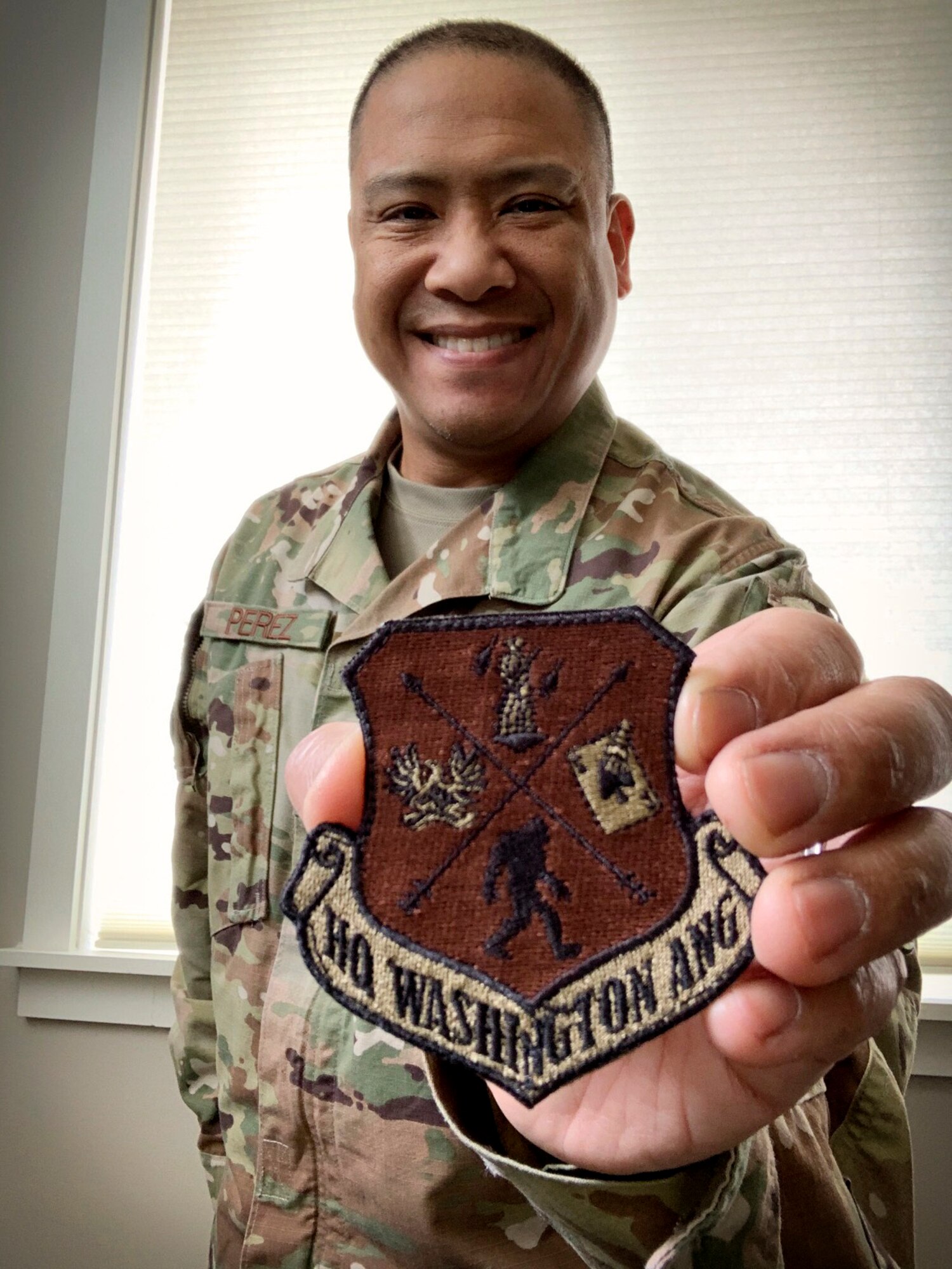 U.S. Air Force Senior Master Sgt. Christopher Perez, Superintendent for recruiting and retention for the Washington Air National Guard shows off the Headquarters patch for the Washington Air National Guard that was part of a recruiting campaign he helped developed for social media, May 4, 2020 at Camp Murray, Wash. (Courtesy photo by Senior Master Sgt. Christopher Perez)