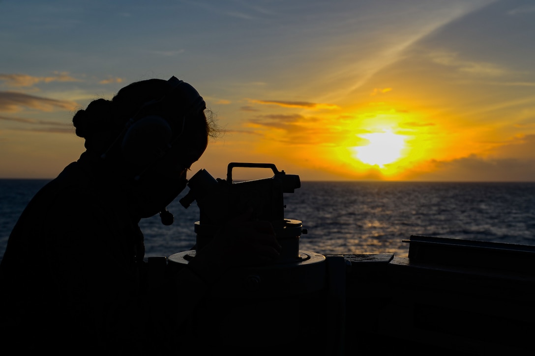 The silhouette of a sailor with the sun behind her.