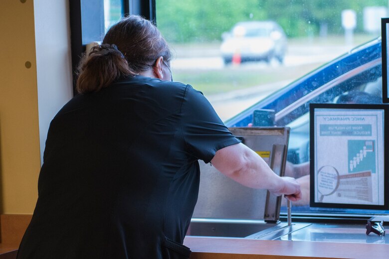 Susan Torres, a pharmacy technician assigned to the Naval Medical Readiness Training Command, gives a patient their prescription through the drive-thru window at Naval Health Clinic Charleston Pharmacy at Joint Base Charleston, S.C., April 24, 2020. The NHCC Pharmacy altered their customer service operations to have the primary way to obtain a prescription be through the drive-thru. Pharmacy personnel are protecting patients and themselves by washing their hands every 30 mins, practicing physical distancing, wearing masks and cleaning routinely.