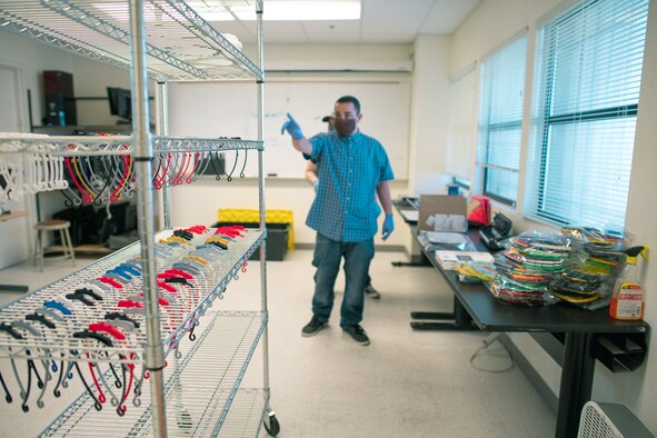 photo of man with gloves and face mask pointing to a shelf of face shield components.