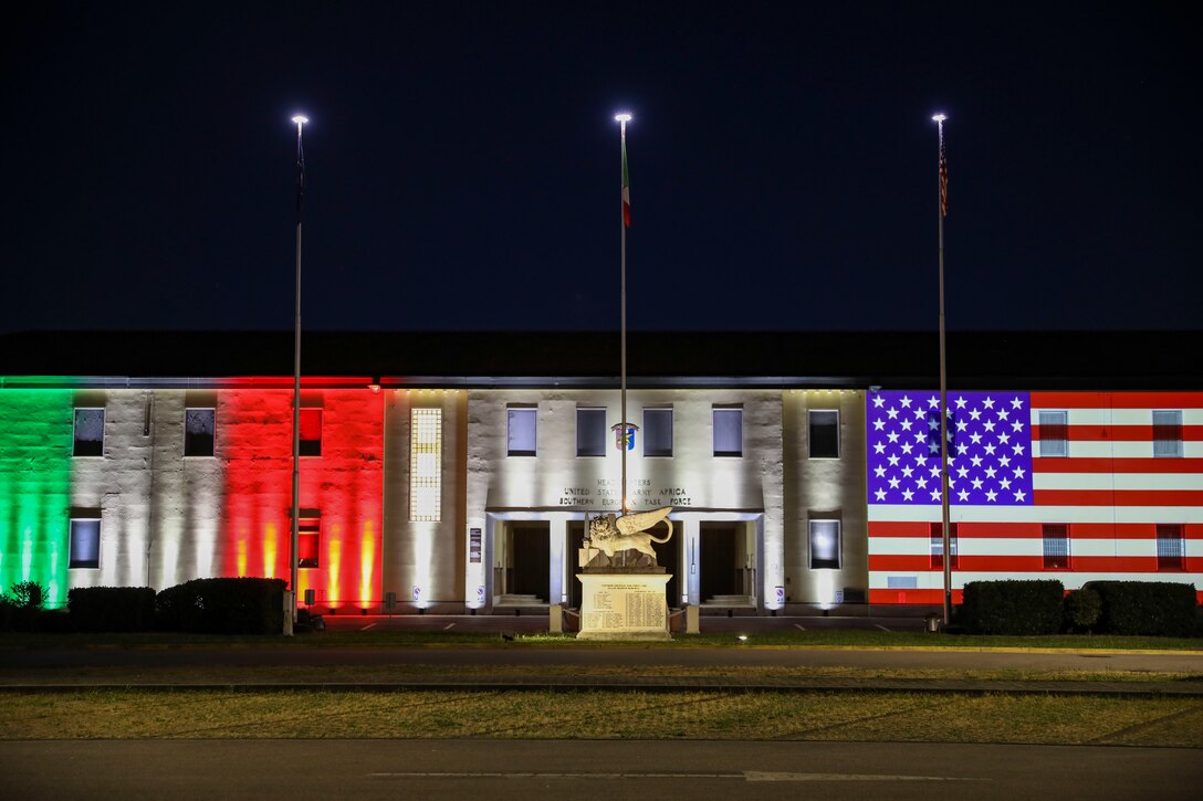 A building illuminated with the Italian and American flags.