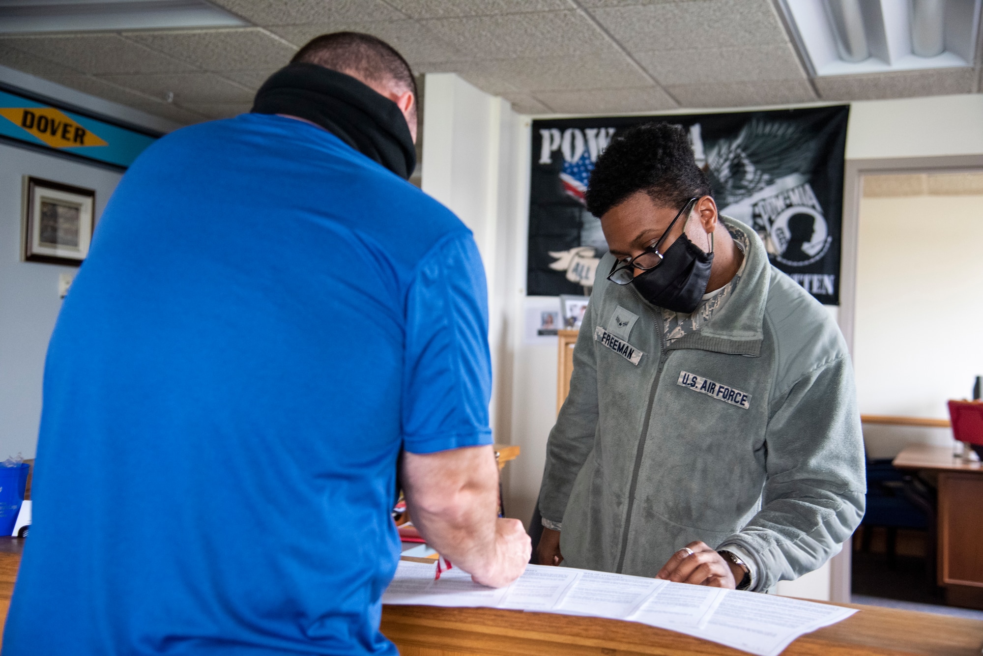 Tech. Sgt. Chuck Broadway, 436th Airlift Wing public affairs NCOIC of media (left), reviews paperwork given to him by Airman 1st Class Malik Freeman, 436th Airlift Wing Legal Office paralegal (right), May 1, 2020, at Dover Air Force Base, Delaware. To combat the spread of COVID-19, those coming in for appointments are asked to bring their own pens. (U.S. Air Force photo by Airman 1st Class Jonathan Harding)