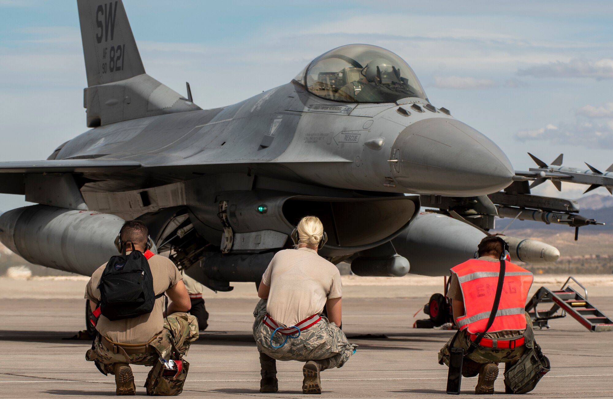 A picture of a group of Airmen sitting in front of a F-16.