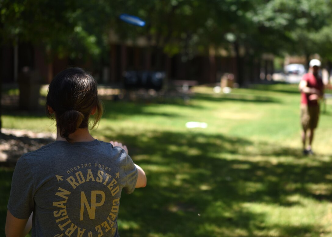 U.S. Air Force Airman 1st Class Robyn Hunsinger, 17th Training Wing photojournalist, moves to catch a frisbee thrown by Senior Airman Zachary Chapman, 17th TRW broadcast journalist, on Goodfellow Air Force Base, Texas, April 28, 2020. Getting sunshine is vital to your physical and mental health. (U.S. Air Force photo by Airman 1st Class Ethan Sherwood)