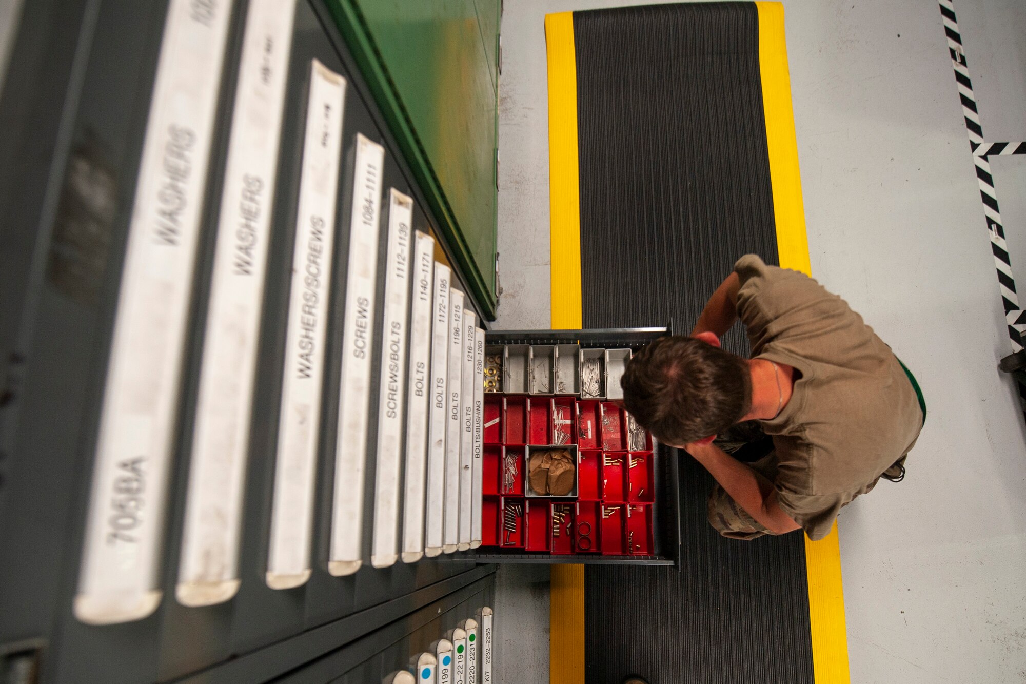A photo of an Airman opening a drawer to look at aircraft parts