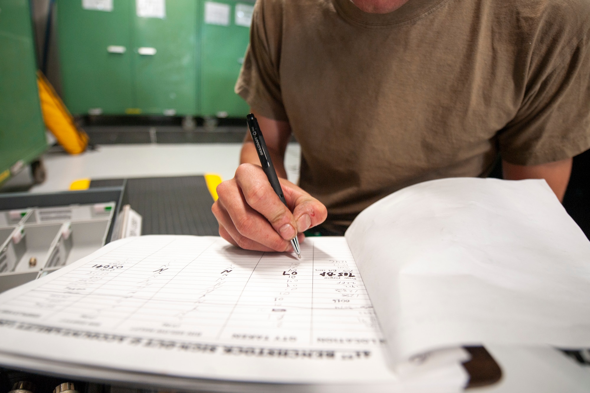 A photo of an Airman writing on a document.