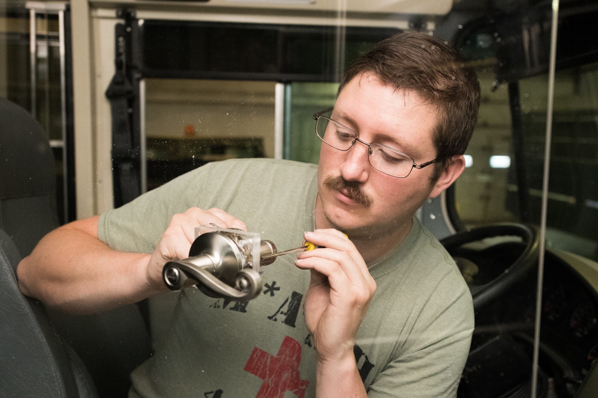 Staff Sgt. Cory Nelson, 436th Logistics Readiness Squadron Ground Transportation Support noncommissioned officer in charge, adds a door handle to a plexiglass partition on a transport bus, April 27, 2020, at Dover Air Force Base, Delaware. Despite being off duty, Nelson and his 436th LRS team modified three transport buses with a partition between the driver’s seat and the passenger section to help mitigate the potential spread of COVID-19 while transporting aircrews to and from the flight line. (U.S. Air Force photo by Mauricio Campino)