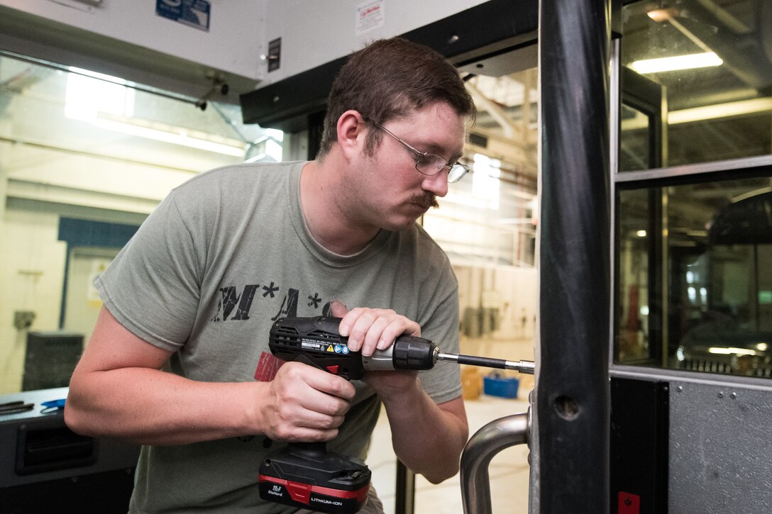 Staff Sgt. Cory Nelson, 436th Logistics Readiness Squadron Ground Transportation Support noncommissioned officer in charge, installs a sheet of plexiglass onto a transport bus April 27, 2020, at Dover Air Force Base, Delaware. Despite being off duty, Nelson and his 436th LRS team dedicated approximately five hours to modify each of the three buses with a partition between the driver’s seat and the passenger section. The installation of plexiglass barriers on transport buses further mitigates the spread of COVID-19, protecting the health and safety of 436th LRS Airmen and aircrew. (U.S. Air Force photo by Mauricio Campino)