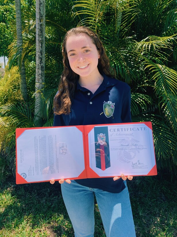 Hannah Mader, a 2020 Summer Leadership and Character Development Academy selectee, poses with her SLCDA shirt and acceptance certificate May 1, 2020. Marine Corps Recruiting Command recently honored 123 students for their achievement as being selected to attend the SLCDA at Marine Corps Base Quantico, Virginia. The academy, now in its ninth year, was originally scheduled to take place June 15-20, 2020, but was cancelled due to the ongoing COVID-19 pandemic. In light of the cancellation, MCRC wanted to recognize the achievements of all the students. (Courtesy Photo)
