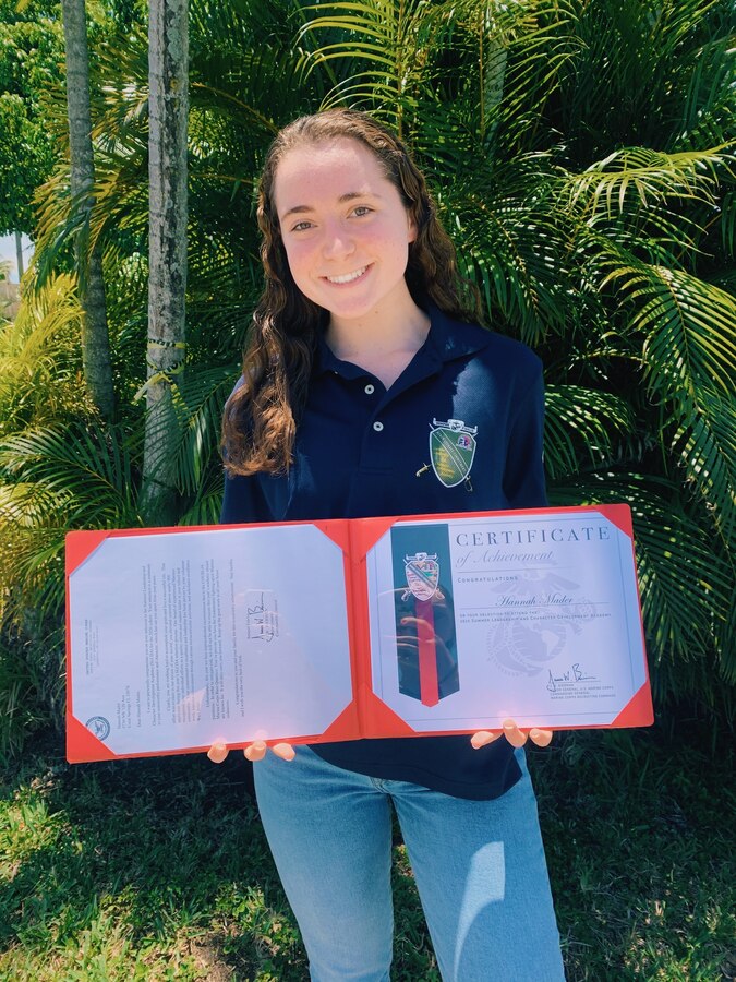 Hannah Mader, a 2020 Summer Leadership and Character Development Academy selectee, poses with her SLCDA shirt and acceptance certificate May 1, 2020. Marine Corps Recruiting Command recently honored 123 students for their achievement as being selected to attend the SLCDA at Marine Corps Base Quantico, Virginia. The academy, now in its ninth year, was originally scheduled to take place June 15-20, 2020, but was cancelled due to the ongoing COVID-19 pandemic. In light of the cancellation, MCRC wanted to recognize the achievements of all the students. (Courtesy Photo)