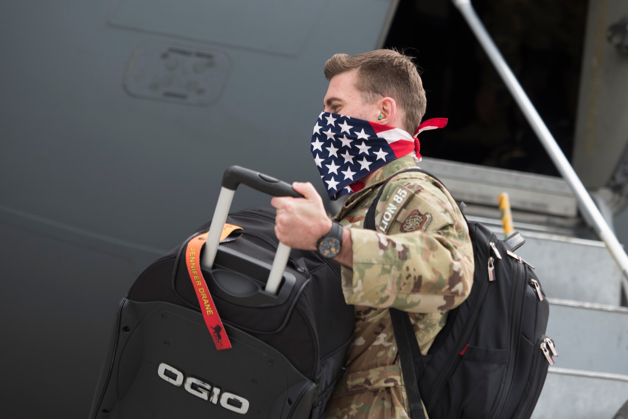 A photo of an Airman bringing his luggage off of a plane.