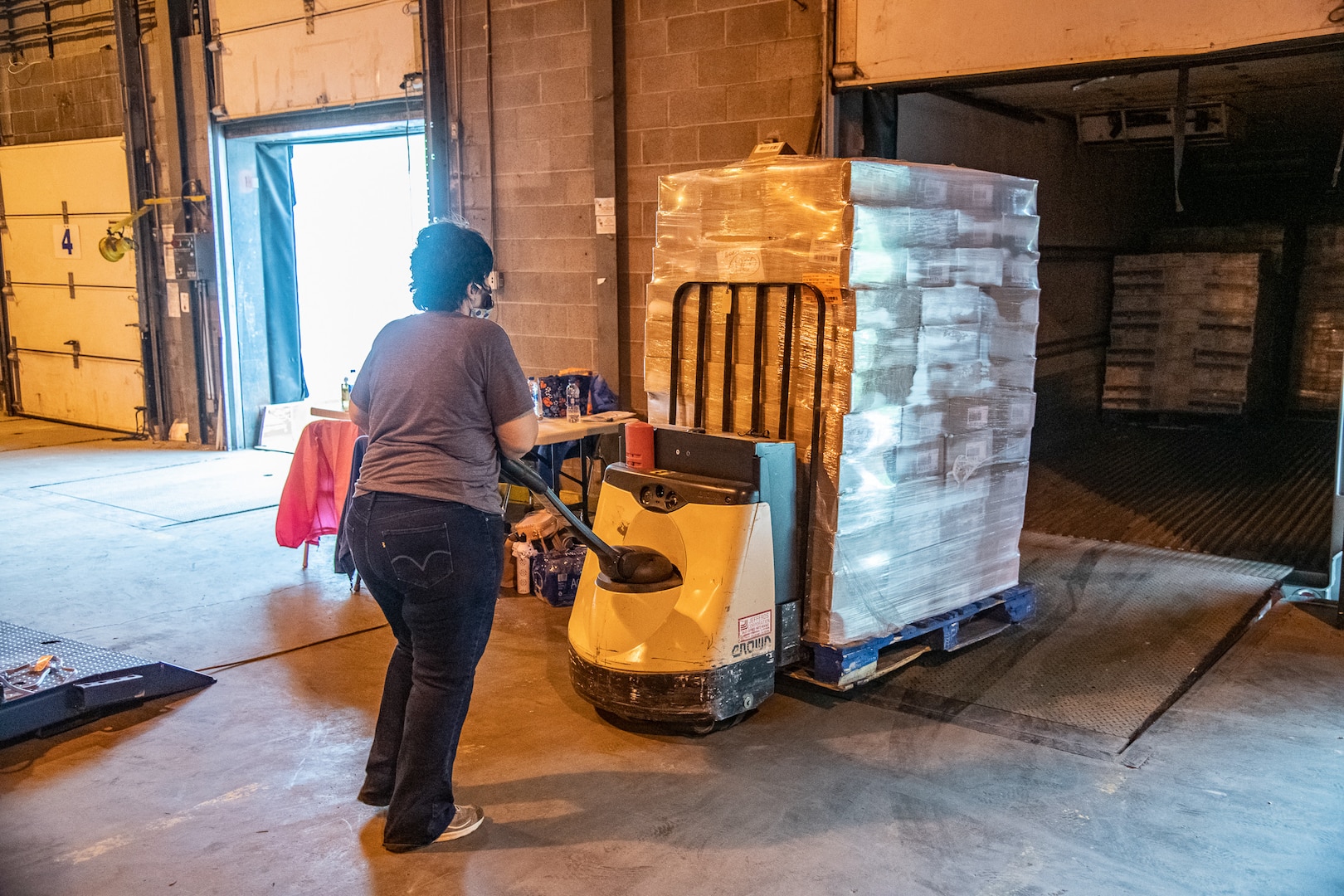 An employees with the Mountaineer Food Bank loads frozen good into a refriderated trailer at a newly created food distribution center at the West Virginia National Guard's Rock Branch facility in Poca, West Virignia, May 05, 2020. The new center is a joint effort between the West Virginia National Guard (WVNG), West Virginia Voluntary Organizations Active in Disasters (VOAD), Mountaineer Food Bank, Facing Hunger Food Bank, and the West Virginia Division of Homeland Security and Emergency Management (WVDHSEM) as the need for supplemental and emergency food services continues to grow across the Mountain State during the ongoing COVID-19 pandemic. (U.S. Army National Guard photo by Edwin L. Wriston)