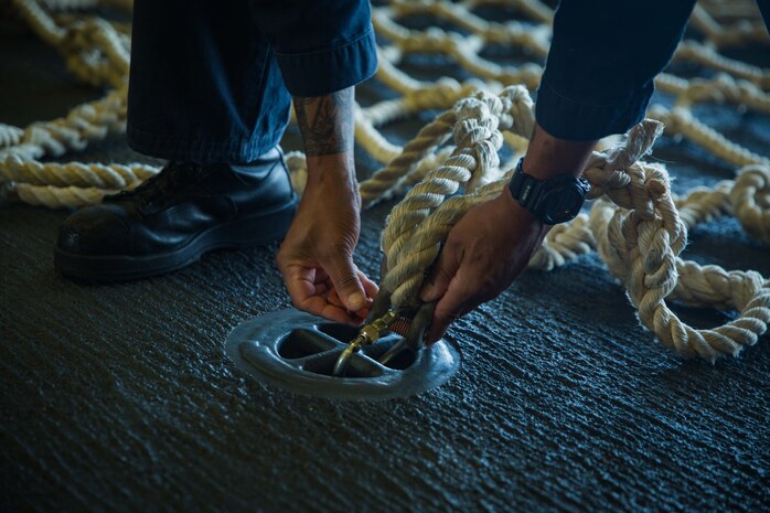 A sailor aboard amphibious assault ship USS America secures a cargo net during a tactical debarkation rehearsal from America, April 28.