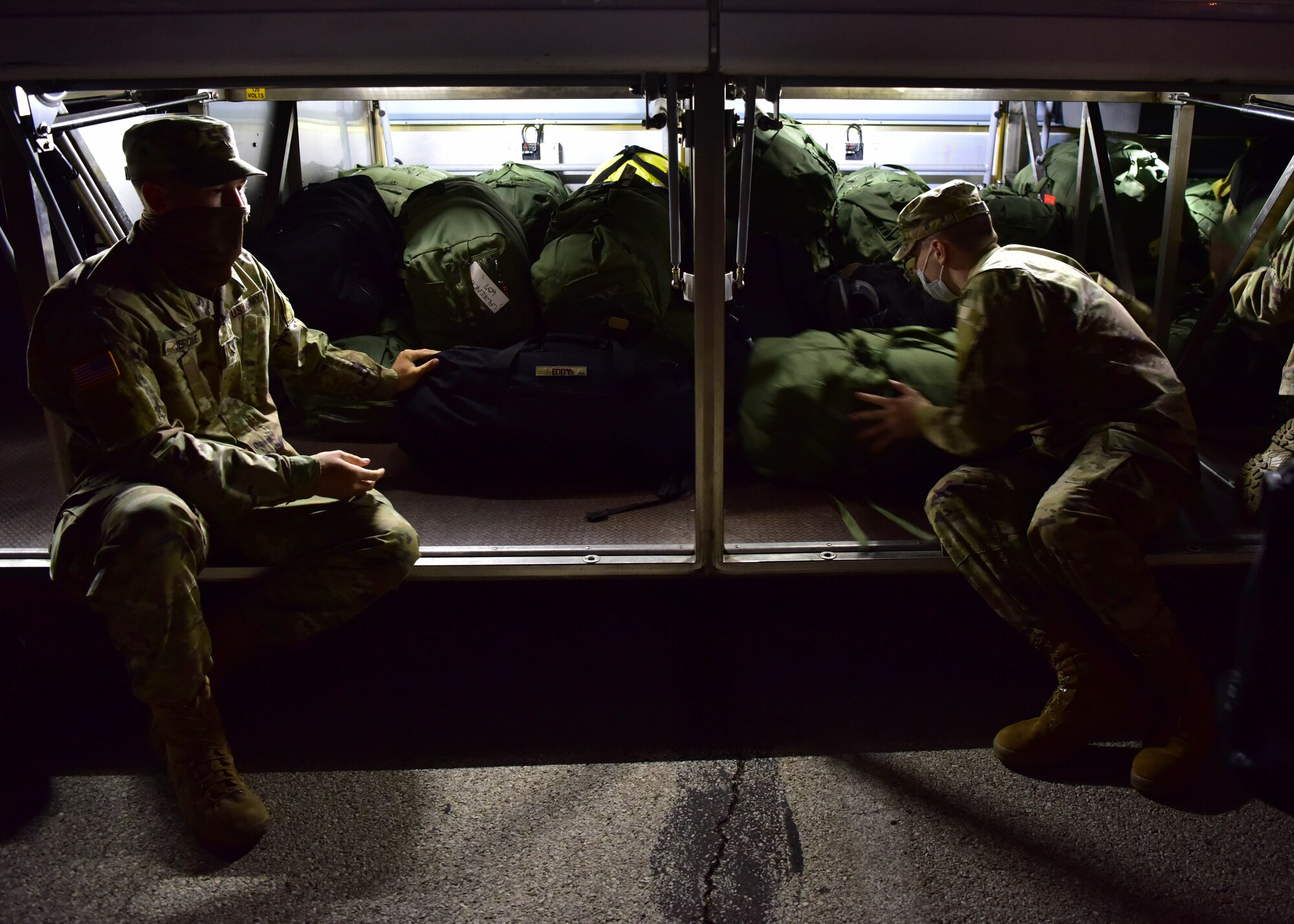 Soldiers with the 344th Military Intelligence Battalion load their bags onto a bus on Goodfellow Air Force Base, Texas, May 5, 2020. The Soldiers used buses instead of the normal airline travel to maintain proper precautions during the COVID-19 restrictions. (U.S. Air Force photo by Staff Sgt. Chad Warren)