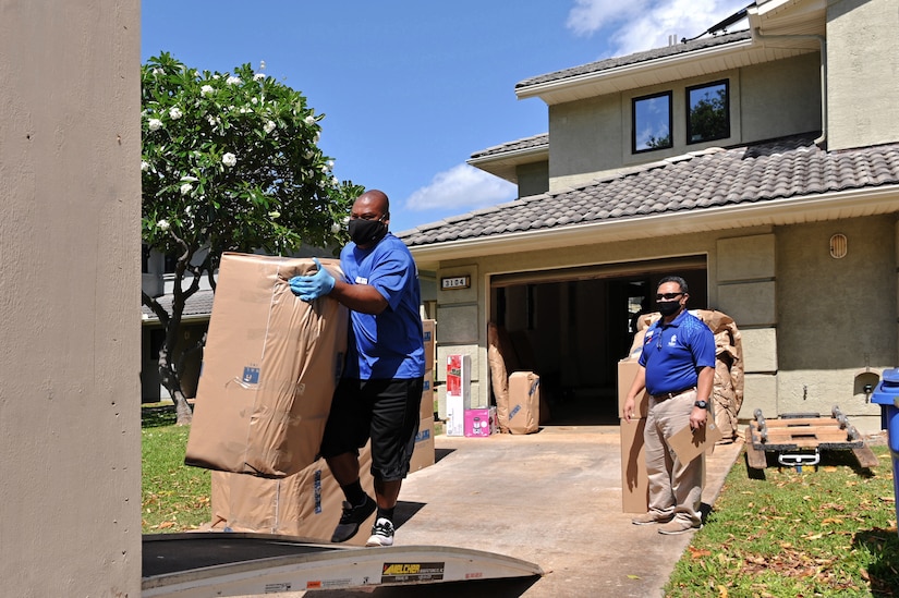 A man carries a large box onto a moving truck.