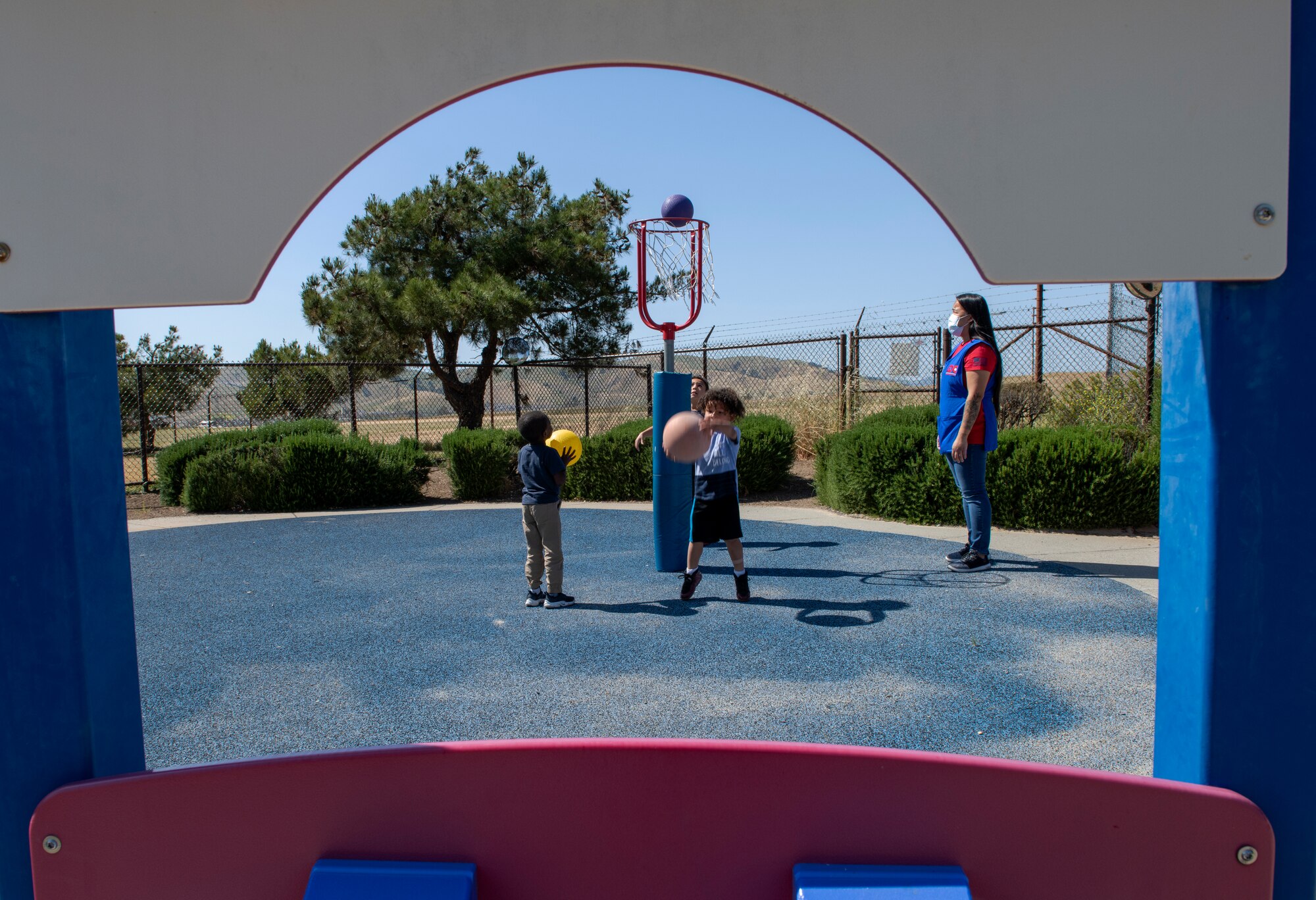 Cheryl Jose, right, 60th Force Support Squadron child and development program technician, supervises children May 1, 2020, as they play outside Child Development Center 3 at Travis Air Force Base, California. Travis AFB has three childcare centers that have cared for military children during the coronavirus pandemic. (U.S. Air Force photo by Tech. Sgt. James Hodgman)