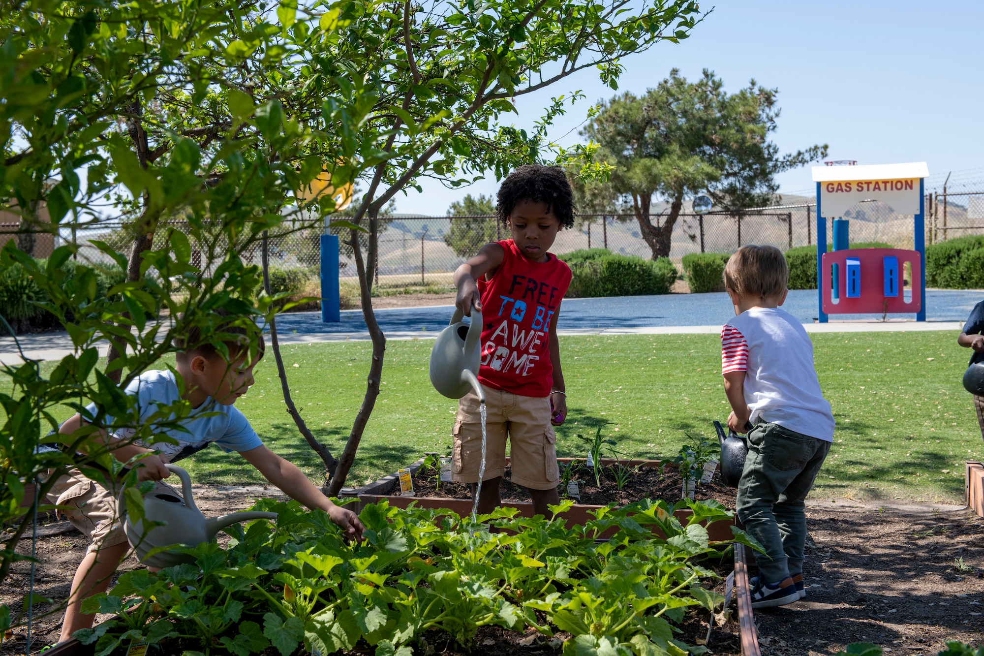 Children water plants May 1, 2020, outside Child Development Center 3 at Travis Air Force Base, California. Travis AFB has three CDCs that have cared for military children during the coronavirus pandemic. (U.S. Air Force photo by Tech. Sgt. James Hodgman)