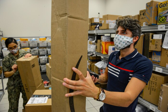 NAPLES, Italy (April 30, 2020) Francesco Ciccarelli, postal clerk (right), and Logistics Specialist Seaman Oralia Ortiz sort and organize incoming mail at the Naval Support Activity (NSA) Naples Support Site post office, attached to Naval Supply Systems Command Fleet Logistics Center (NAVSUP FLC) Sigonella, April 30, 2020. Commander, U.S. Naval Forces Europe-Africa/ U.S. 6th Fleet, headquartered in Naples, Italy, oversees joint and naval operations, often in concert with Allied, joint, and interagency partners, in order to advance U.S. national interests and security and stability in Europe and Africa. (U.S. Navy photo by Mass Communication Specialist Chief Justin Stumberg/Released)