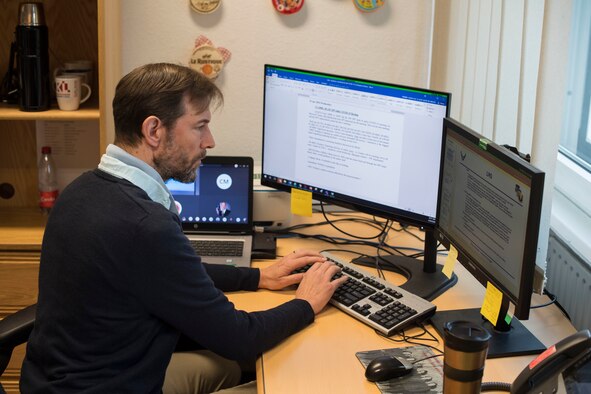 A man types on a computer keyboard at his desk.