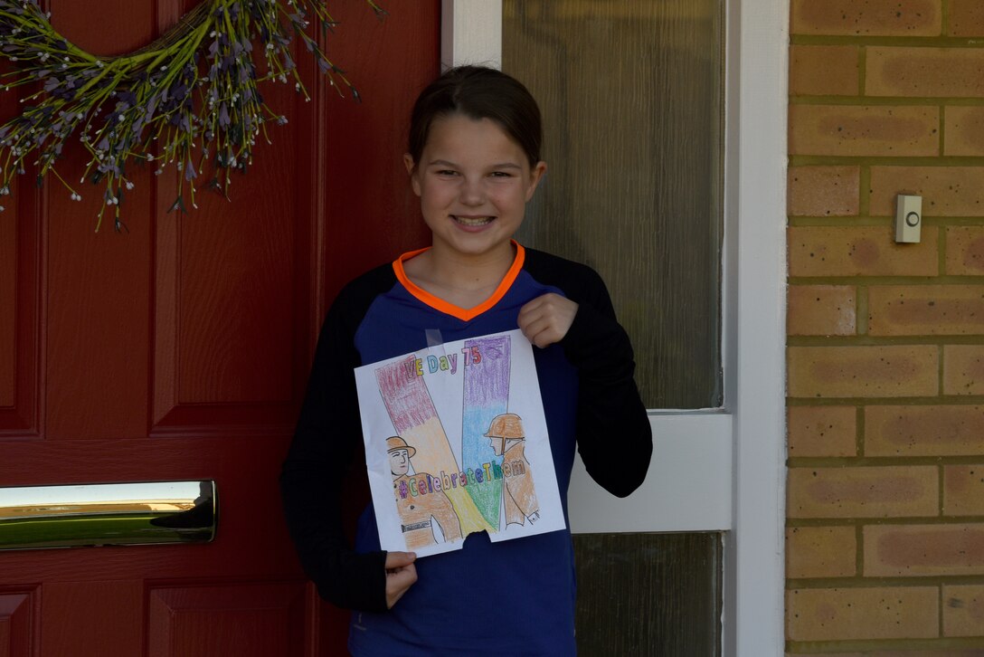 A child of a U.S. Air Force Airman displays Victory in Europe Day artwork in Liberty Village at Royal Air Force Lakenheath, England, May 6, 2020. The U.S. Embassy and Consulates in the U.K. provided coloring posters on their website for families to print and display, as a way to celebrate the 75th anniversary of VE Day amid the COVID-19 pandemic. (U.S. Air Force photo by Airman 1st Smith Rhonda Smith)