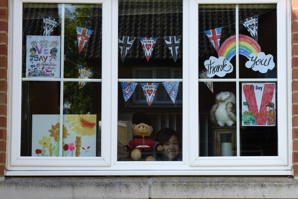A child of a U.S. Air Force Airman displays Victory in Europe Day artwork in their windows in Liberty Village at Royal Air Force Lakenheath, England, May 6, 2020. Coloring poster designs to print and display can be found on the U.S. Embassy & Consulates in the United Kingdom website, as a way to celebrate the 75th anniversary of VE Day despite the current COVID-19 pandemic. (U.S. Air Force photo by Airman 1st Smith Rhonda Smith)