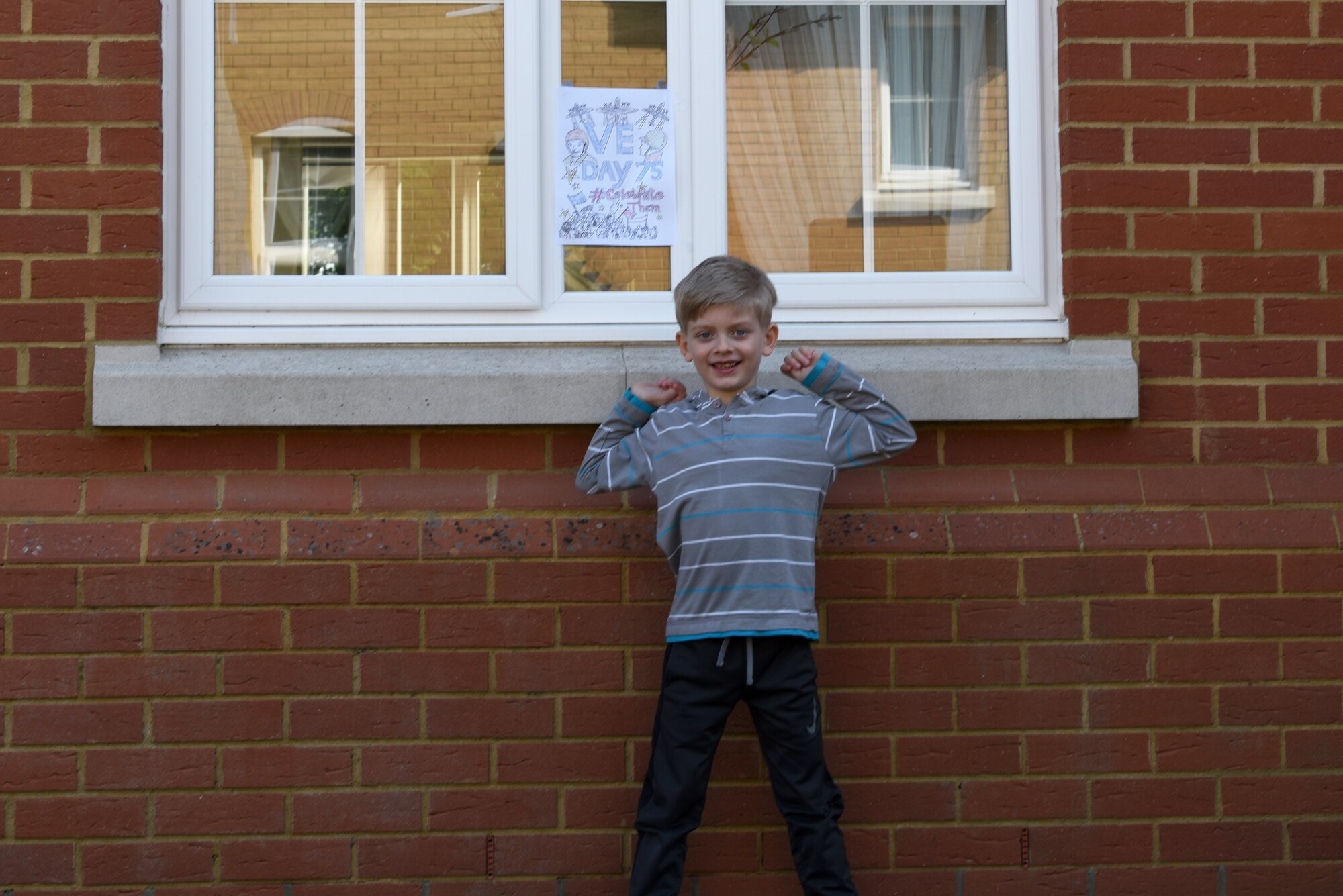 A child of a U.S. Air Force Airman displays Victory in Europe Day artwork in their window in Liberty Village at Royal Air Force Lakenheath, England, May 6, 2020. On May 8, the U.K. will join the U.S. and allies around the world to mark the 75th anniversary of VE Day, with virtual programs to avoid the spread of COVID-19. (U.S. Air Force photo by Airman 1st Smith Rhonda Smith)