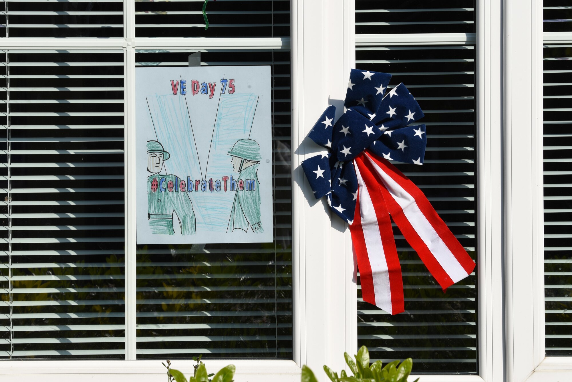 Victory in Europe Day artwork is displayed in a window in Liberty Village at Royal Air Force Lakenheath, England, May 6, 2020. On May 8, the U.K. will join the U.S. and allies around the world to mark the 75th anniversary of VE Day, with virtual programs to avoid the spread of COVID-19. (U.S. Air Force photo by Airman 1st Smith Rhonda Smith)