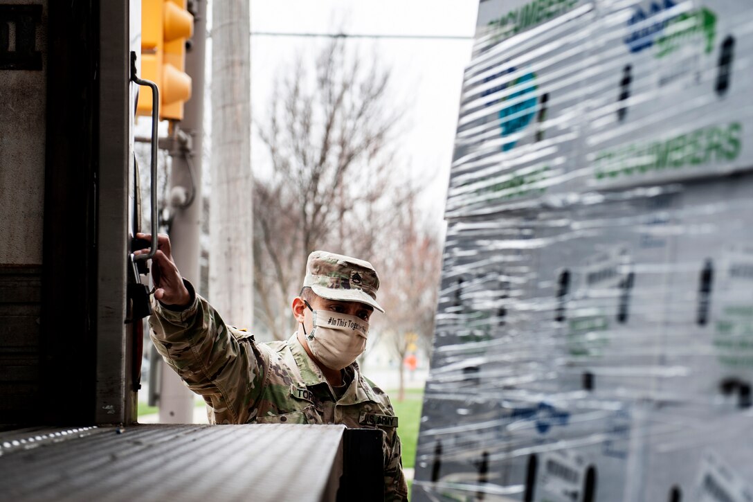 A soldier unloads pallets of fresh produce.