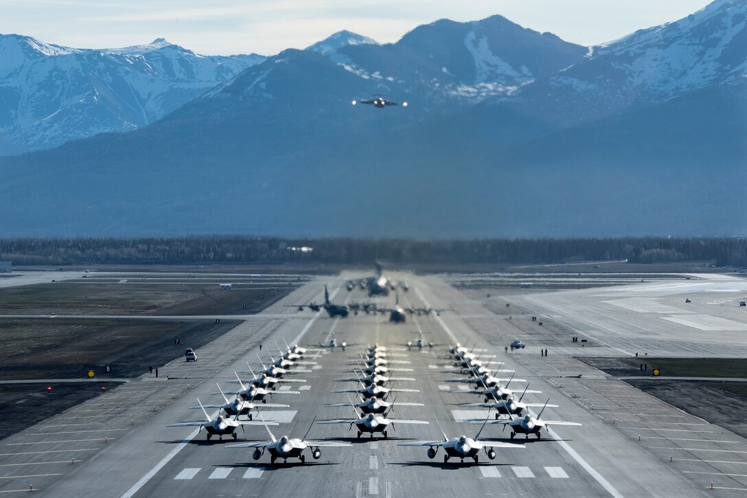 U.S. Air Force F-22 Raptors, E-3 Sentrys, C-17 Globemaster IIIs, C-130J Herculeses and C-12F Hurons participate in a close formation taxi known as an elephant walk, while a Globemaster III flies over the formation, at Joint Base Elmendorf-Richardson, Alaska, May 5, 2020. This event displayed the ability of the 3rd Wing, 176th Wing and the 477th Fighter Group to maintain constant readiness throughout COVID-19 by Total Force Integration between active-duty, Guard and Reserve units to continue defending the U.S. homeland and ensuring a free and open Indo-Pacific.