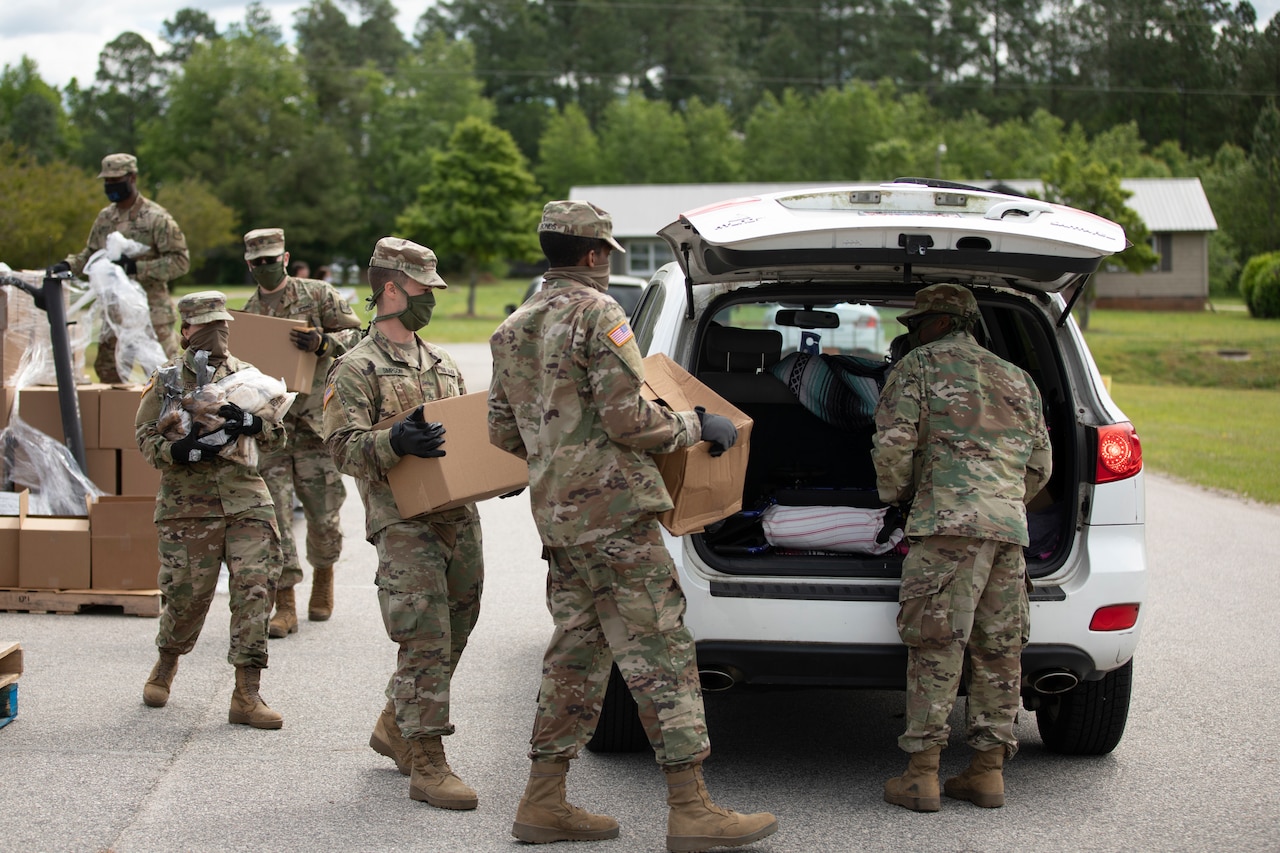 Soldiers loading boxes of food into a vehicle.