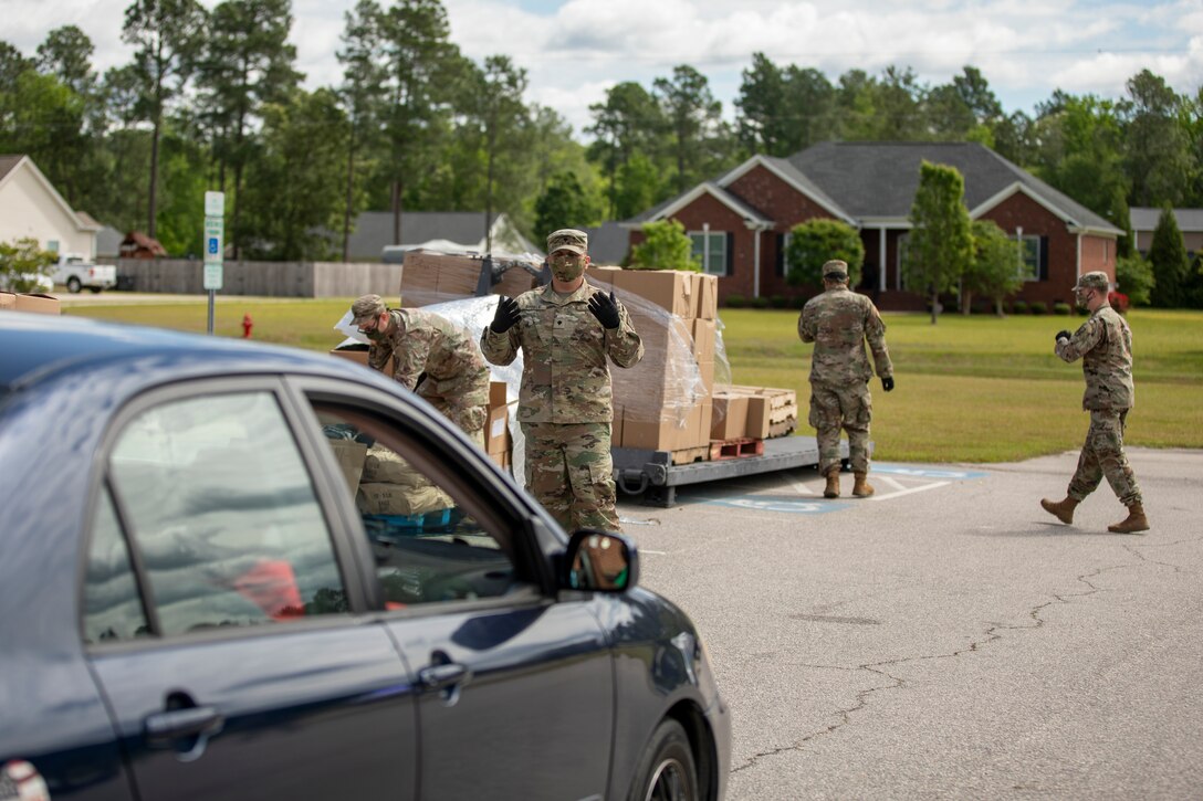 Soldiers load boxes of food into a vehicle.