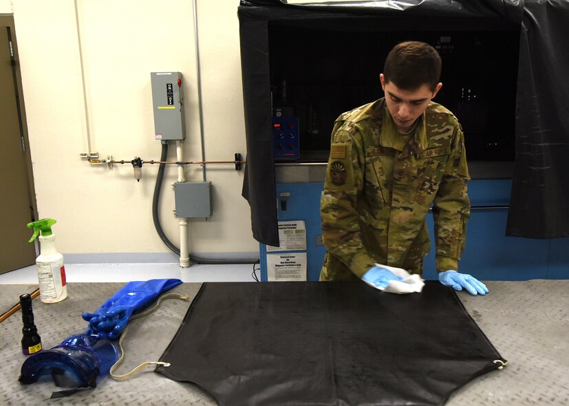 Photo of a U.S. Air Force Airman sanitizing protective equipment on a table.