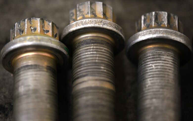A close-up photo of three aircraft screws on a table.