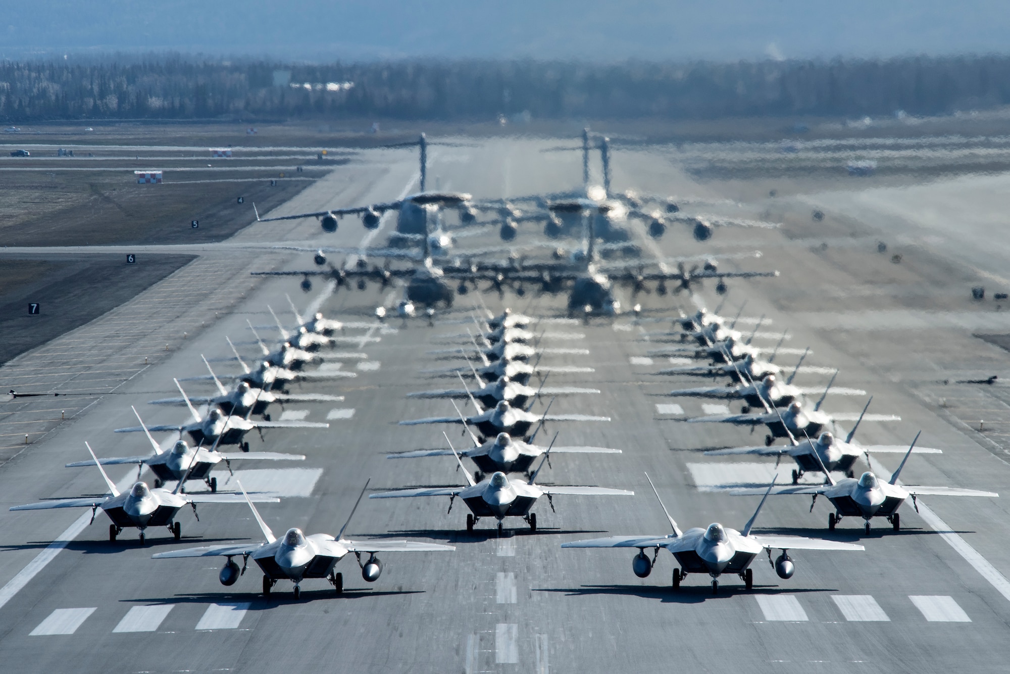 U.S. Air Force F-22 Raptors, E-3 Sentrys, C-17 Globemaster IIIs, C-130J Herculeses and C-12F Hurons participate in a close formation taxi known as an elephant walk at Joint Base Elmendorf-Richardson, Alaska, May 5, 2020. This event displayed the ability of the 3rd Wing, 176th Wing and the 477th Fighter Group to maintain constant readiness throughout COVID-19 by Total Force Integration between active-duty, Guard and Reserve units to continue defending the U.S. homeland and ensuring a free and open Indo-Pacific.