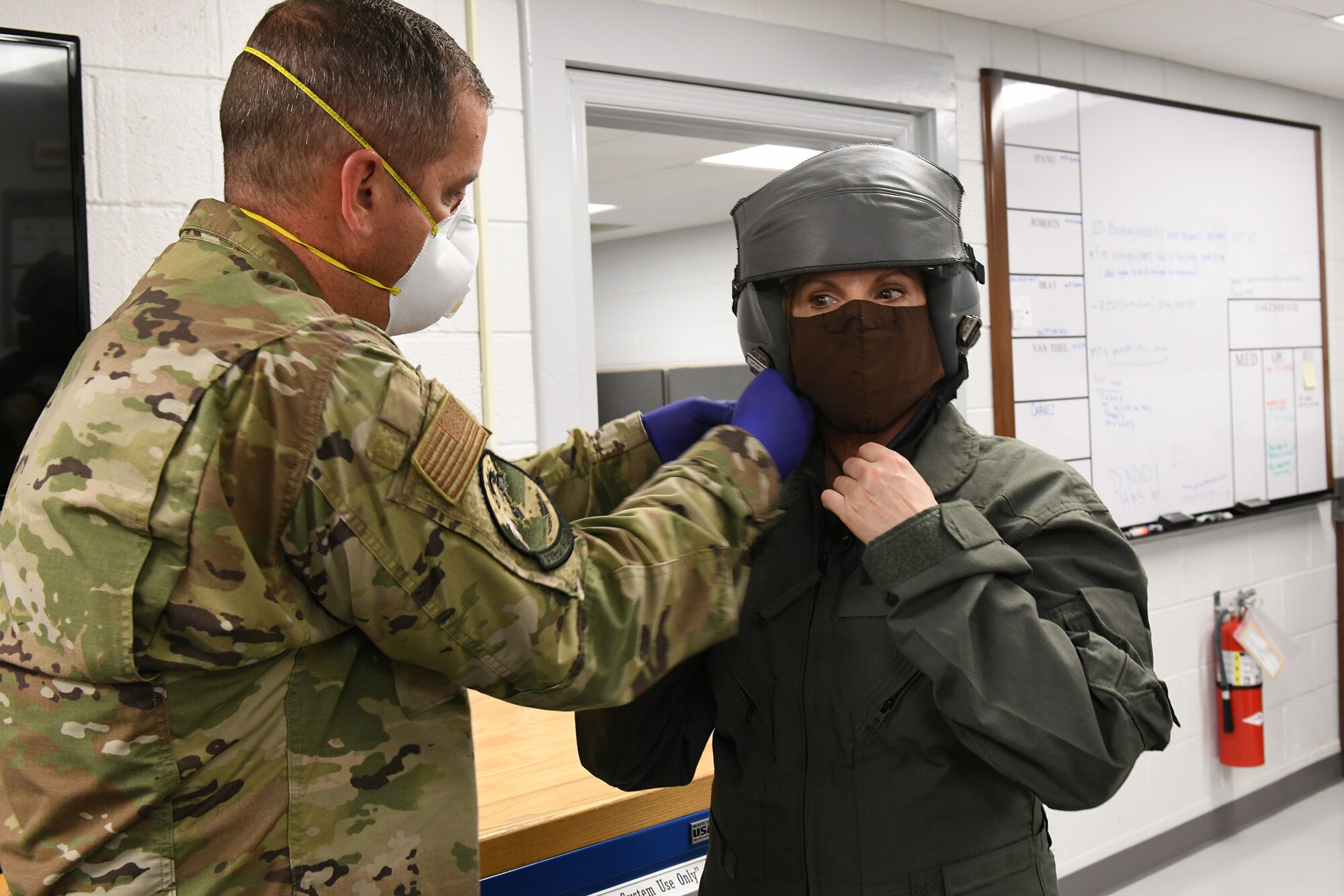 Photo shows Col. Farrell having her straps on her helmet being adjusted.