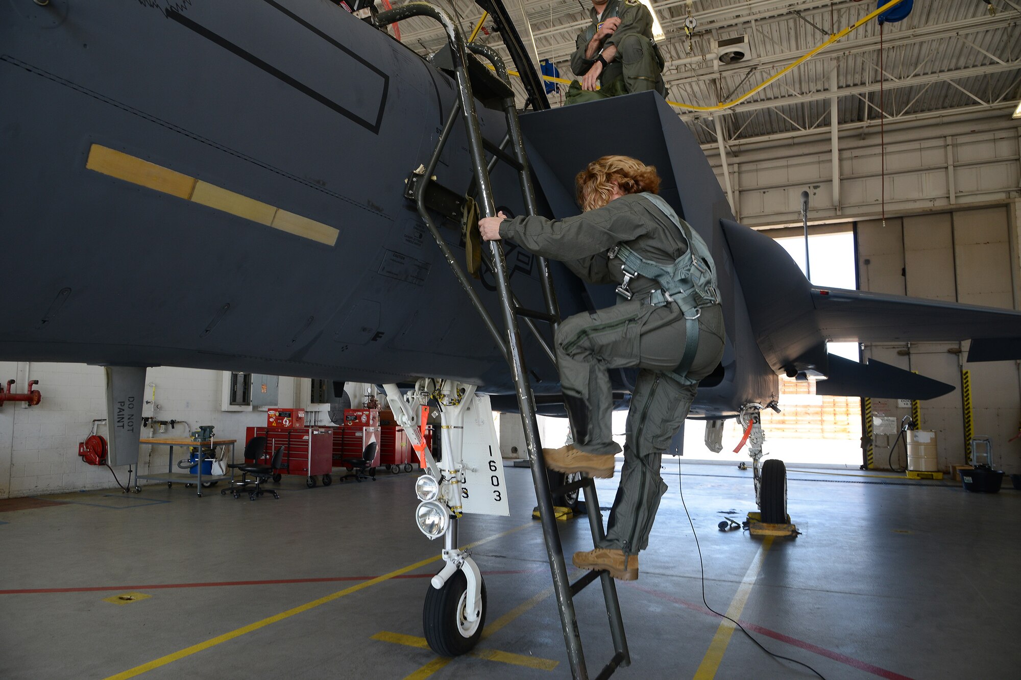 Photo shows Col. Farrell climbing a ladder up into the cockpit of an F-15 aircraft.