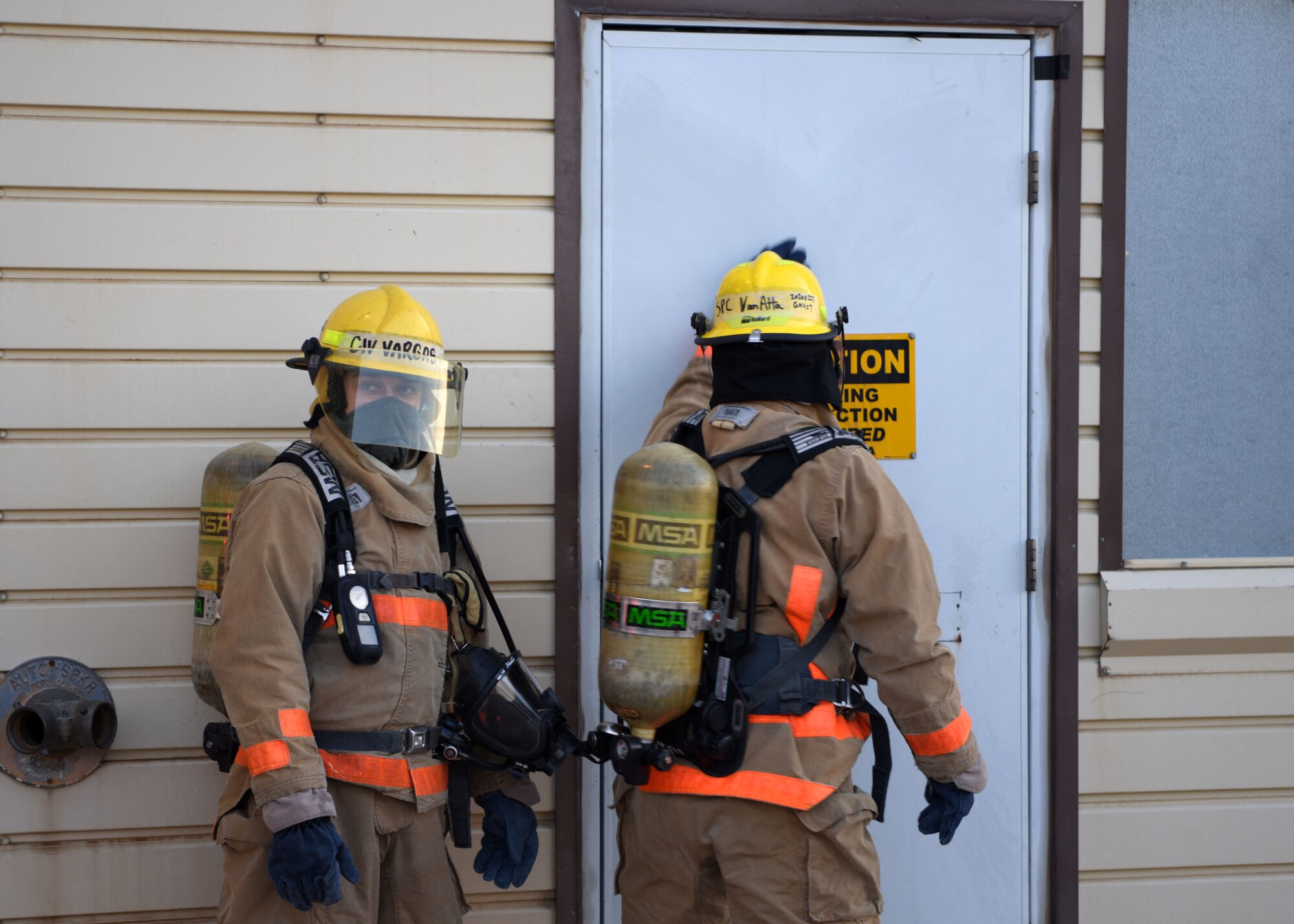 The 312th Training Squadron students feel a door for heat before entering a building at the Louis F. Garland Department of Defense Fire Academy on Goodfellow Air Force Base, Texas, May 6, 2020. Students were tested on what they knew and how well they accomplished set tasks. (U.S. Air Force photo by Airman 1st Class Ethan Sherwood)