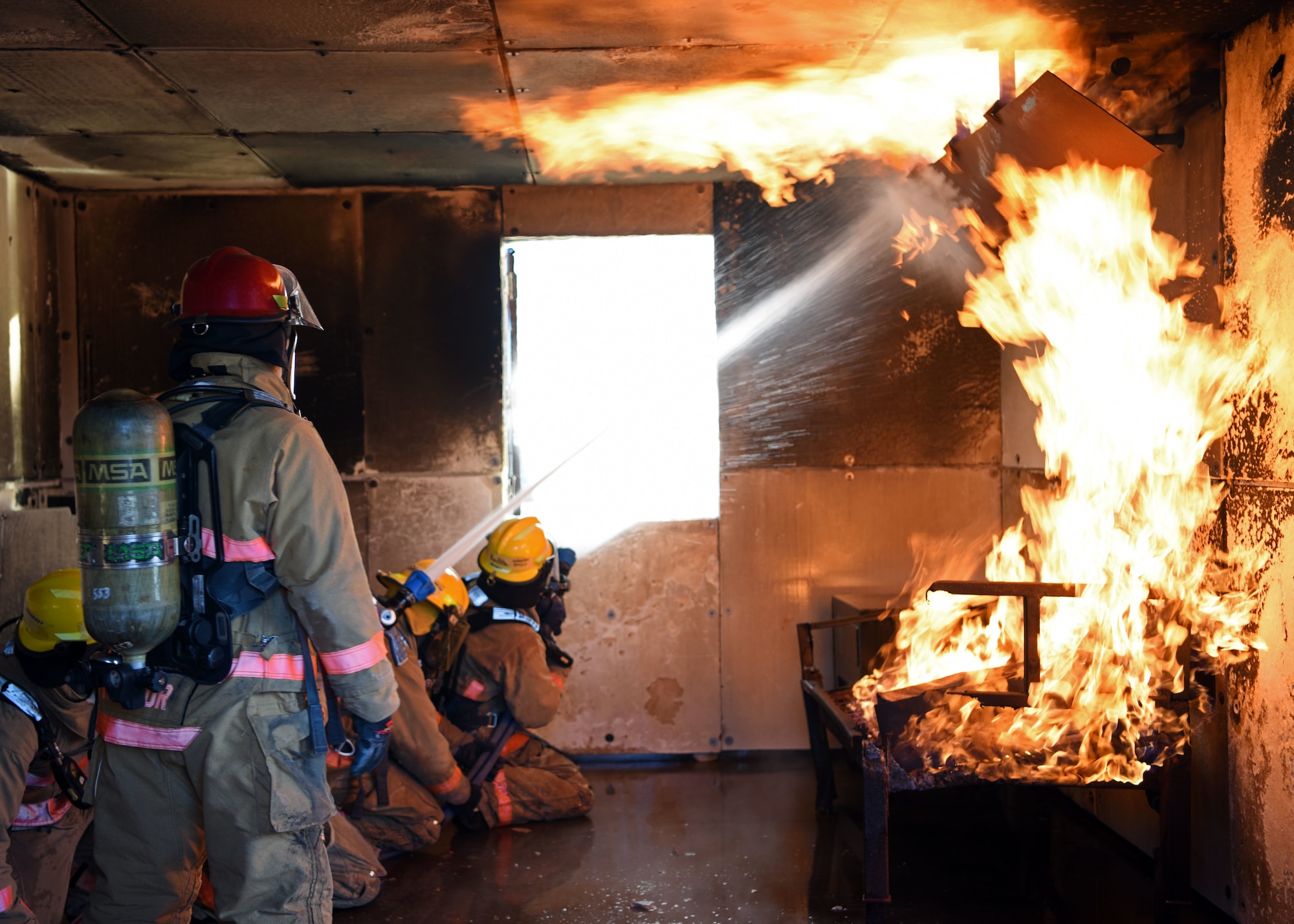 A team of students fight a fire while ventilating the room at the Louis F. Garland Department of Defense Fire Academy on Goodfellow Air Force Base, Texas, May 6, 2020. The students were assigned to three units which all had different roles to play during a structure fire. (U.S. Air Force photo by Airman 1st Class Ethan Sherwood)