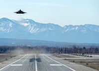 A U.S. Air Force F-22 Raptor takes off while other Raptors taxi to the runway following a close formation taxi known as an elephant walk, at Joint Base Elmendorf-Richardson, Alaska, May 5, 2020. This event displayed the ability of the 3rd Wing, 176th Wing and the 477th Fighter Group to maintain constant readiness throughout COVID-19 by Total Force Integration between active-duty, Guard and Reserve units to continue defending the U.S. homeland and ensuring a free and open Indo-Pacific.