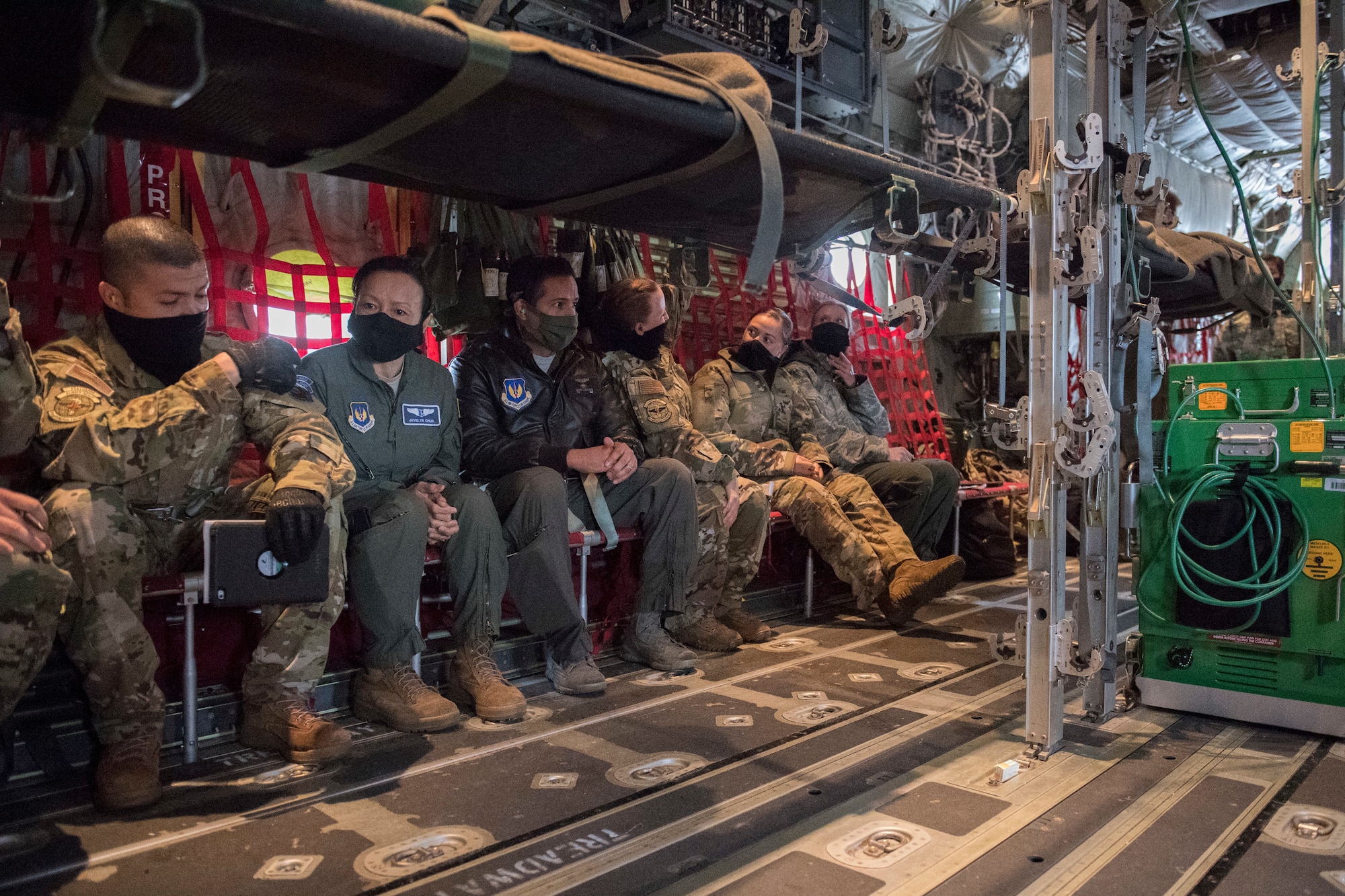 A row of Airmen sit aboard an aircraft.