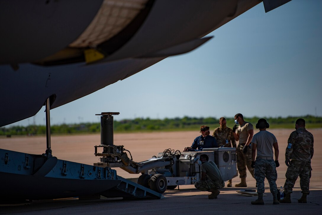 Airmen assigned to Dyess Air Force Base, Texas load cargo onto a C-17 Globemaster III assigned to Joint Base Charleston, S.C., April 25, 2020. The cargo is part of a Bomber Task Force mission consisting of four B-1B Lancers and approximately 200 Airmen at Anderson Air Force Base, Guam. (U.S. Air Force photo by Airman 1st Class Colin Hollowell)