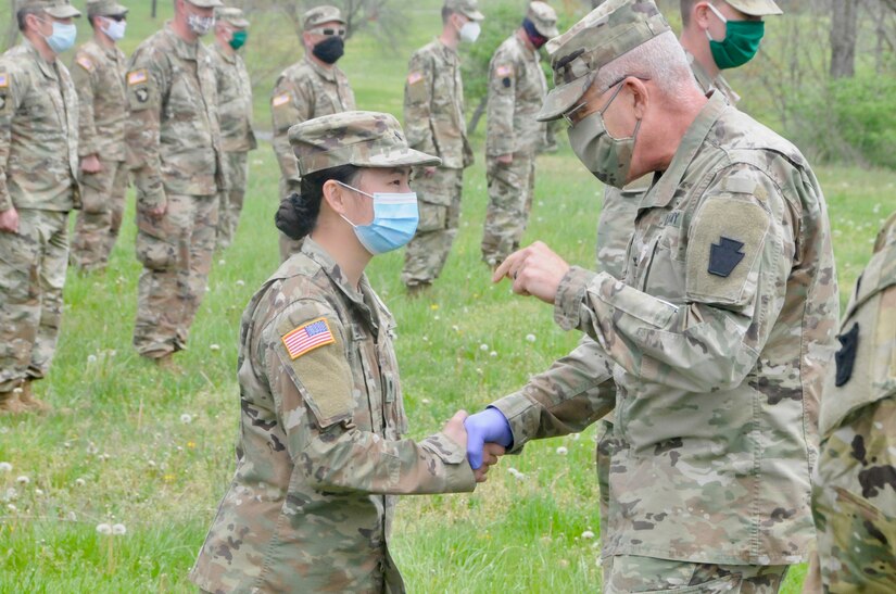 U.S. Army Spc. Kylee Pavlick, combat medic with Headquarters and Headquarters Company, 28th Expeditionary Combat Aviation Brigade, receives a coin from Col. Howard Lloyd, commander of the 28th ECAB. Pavlick works full-time as a nurse at Geisinger Holy Spirit, a hospital near Harrisburg, and currently cares for COVID-19 patients.