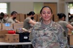 U.S. Army Spc. Kimberly Ortiz of the California Army National Guard’s Alpha Company, 223rd Military Intelligence Battalion, 115th Regional Support Group, stands proudly in front of her unit May 5, 2020, at the Solano Food Bank in Fairfield, California, as her peers wear face masks Ortiz and her mother provided.