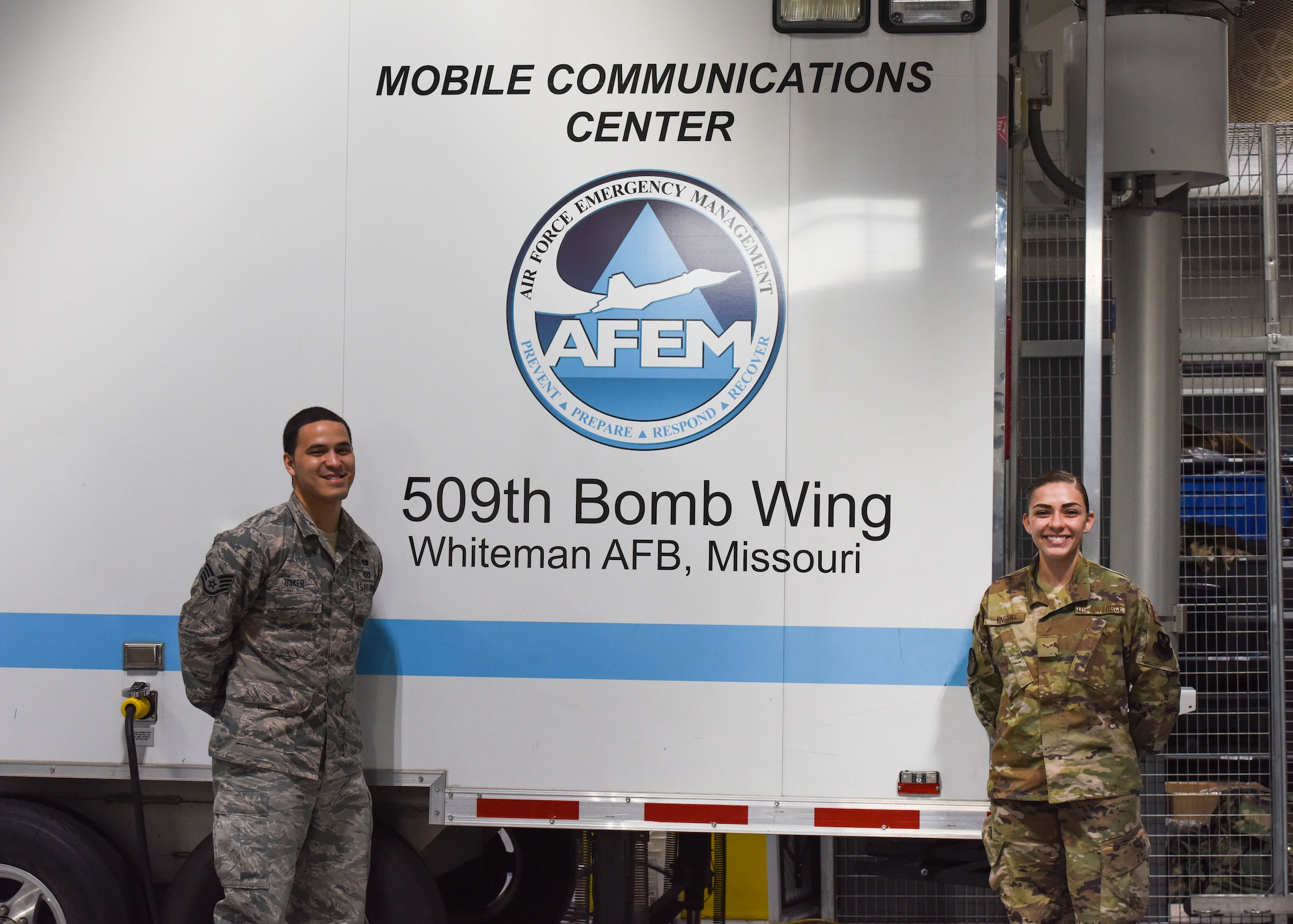 Staff Sergeant Kenneth Baker, assigned to the 509th Emergency Management Flight, assistant Non-commissioned Officer in charge of logistics, and Airman 1st Class Cassidy Knight, assigned to the Emergency Management Flight, plans and operations stand in front of the Emergency Management Mobile Communications Center, used during emergency situations in remote locations or in the event of damaged infrastructure.  Emergency management personnel operate out of the Emergency Operations Center when activated, to execute Installation Emergency Response Plan, which includes specific medical disease containment procedures and instructions.