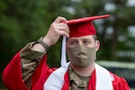 North Carolina Army National Guard Cpl. Chase Boozer, a fire direction specialist with 5th Battalion, 113th Field Artillery Regiment, adjusts the tassel on his graduation cap at the Orange County Emergency Operations Center in Hillsborough, North Carolina, May 5, 2020. Boozer was set to participate in his graduation ceremony with North Carolina State University on May 9 but it was canceled due to COVID-19.