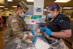 U.S. Army Spc. Kyla Bowman, left, culinary specialist, Foxtrot Company, 250th Brigade Support Battalion, New Jersey Army National Guard, prepares a Stromboli while Head Cook Casie Smickle observes at Veterans Haven North, Glen Gardner, N.J., April 30, 2020. Five New Jersey National Guard Soldiers and three Airmen are assisting the kitchen staff, which is responsible for preparing 2,400 meals a day for residents of the Haven and the Hunterdon Developmental Center.