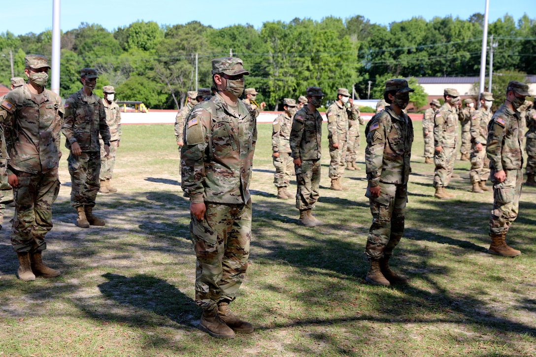 Troops wearing face masks line up in formation.