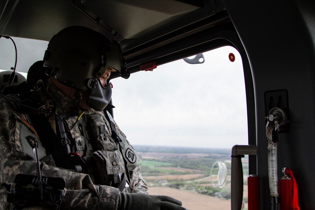 A soldier flying in a helicopter.