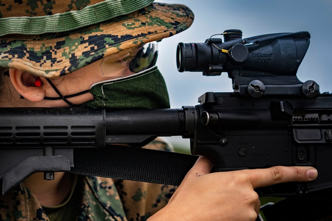 A Marine looks through a scope on a rifle.